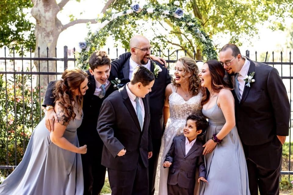 A bride and groom are posing for a picture with their wedding party.