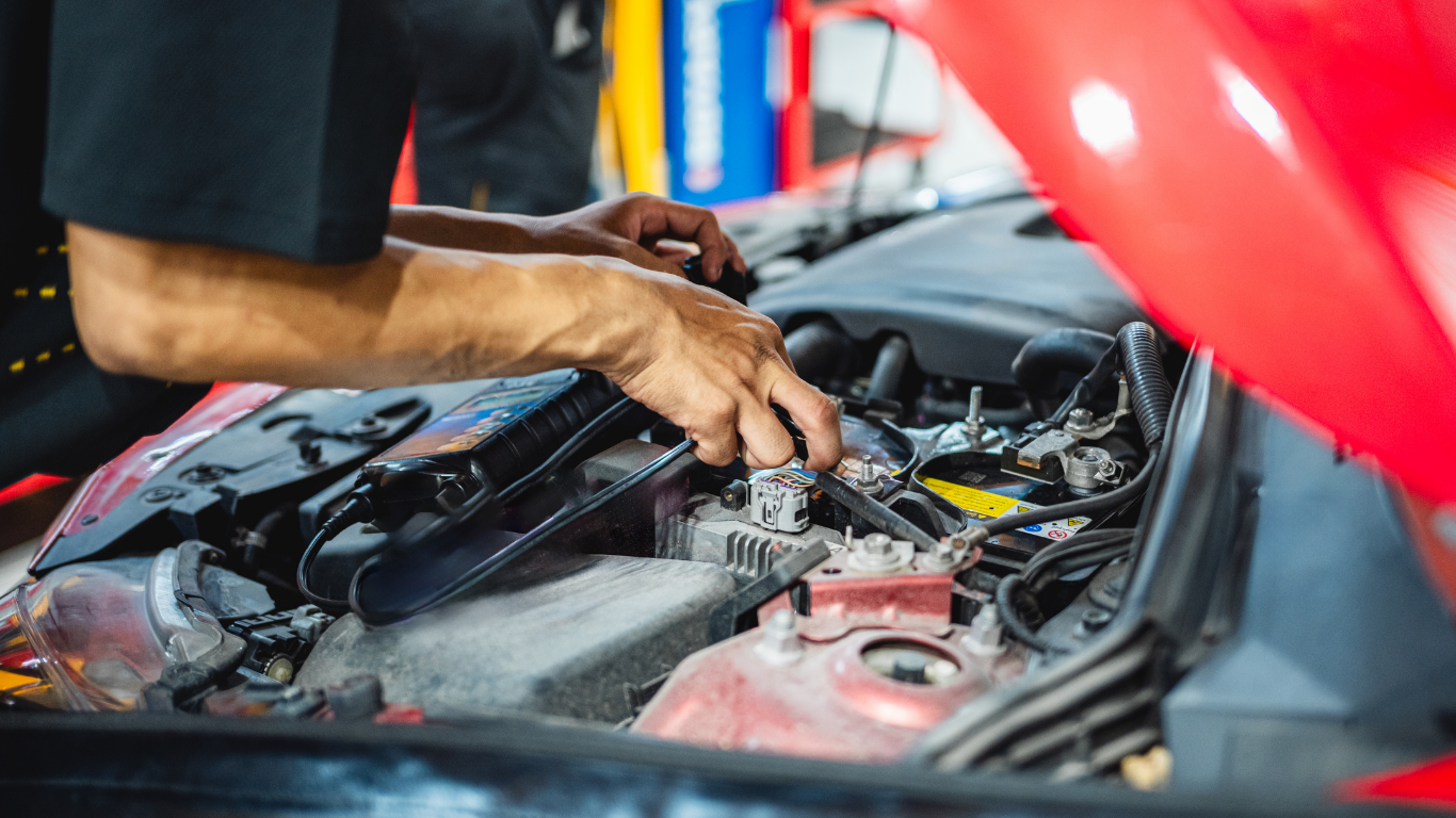 Mechanic working on the engine of a red car in a garage.