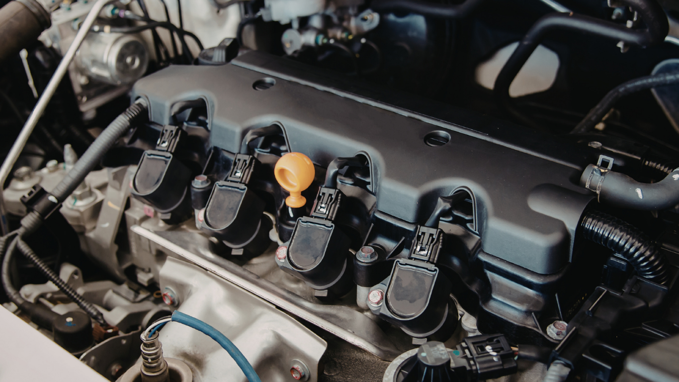 Car engine with visible spark plugs and a yellow oil cap.