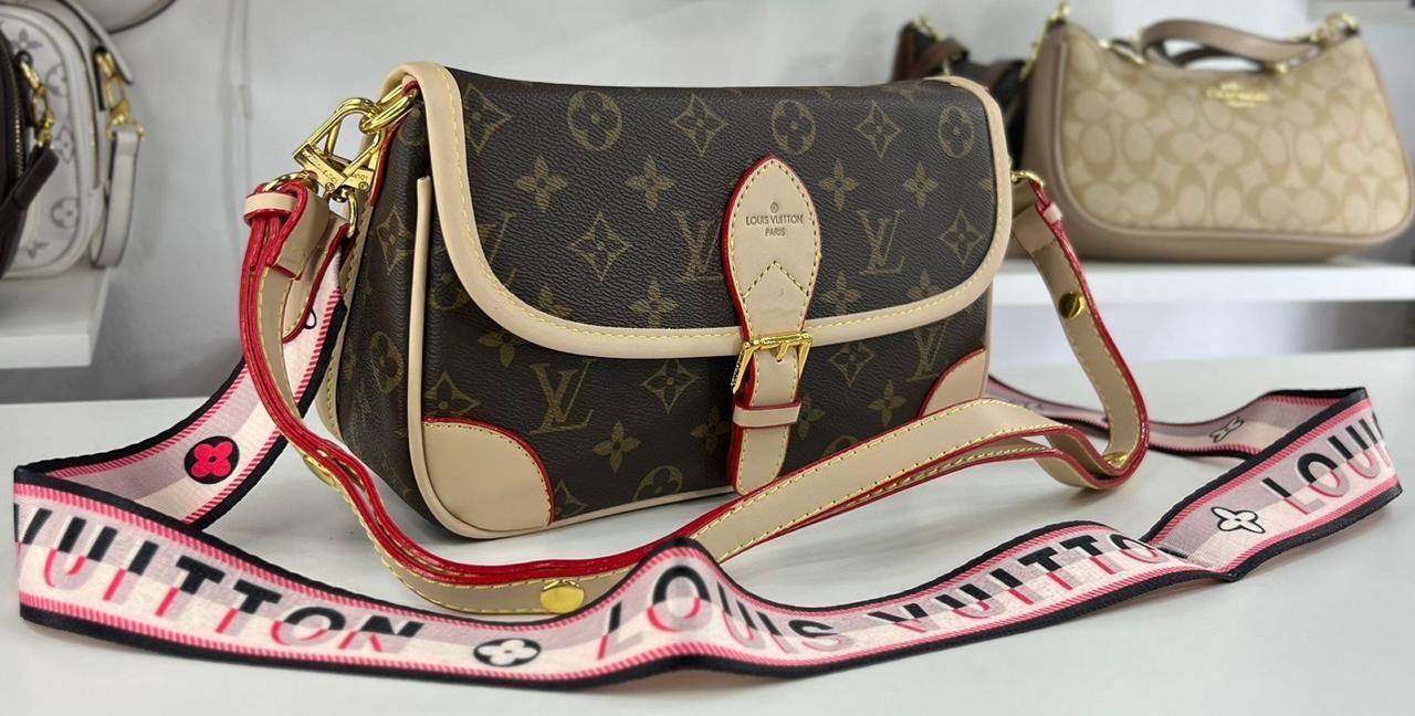 Bolso bandolera Louis Vuitton con monograma marrón y correa rosa, en exposición.
