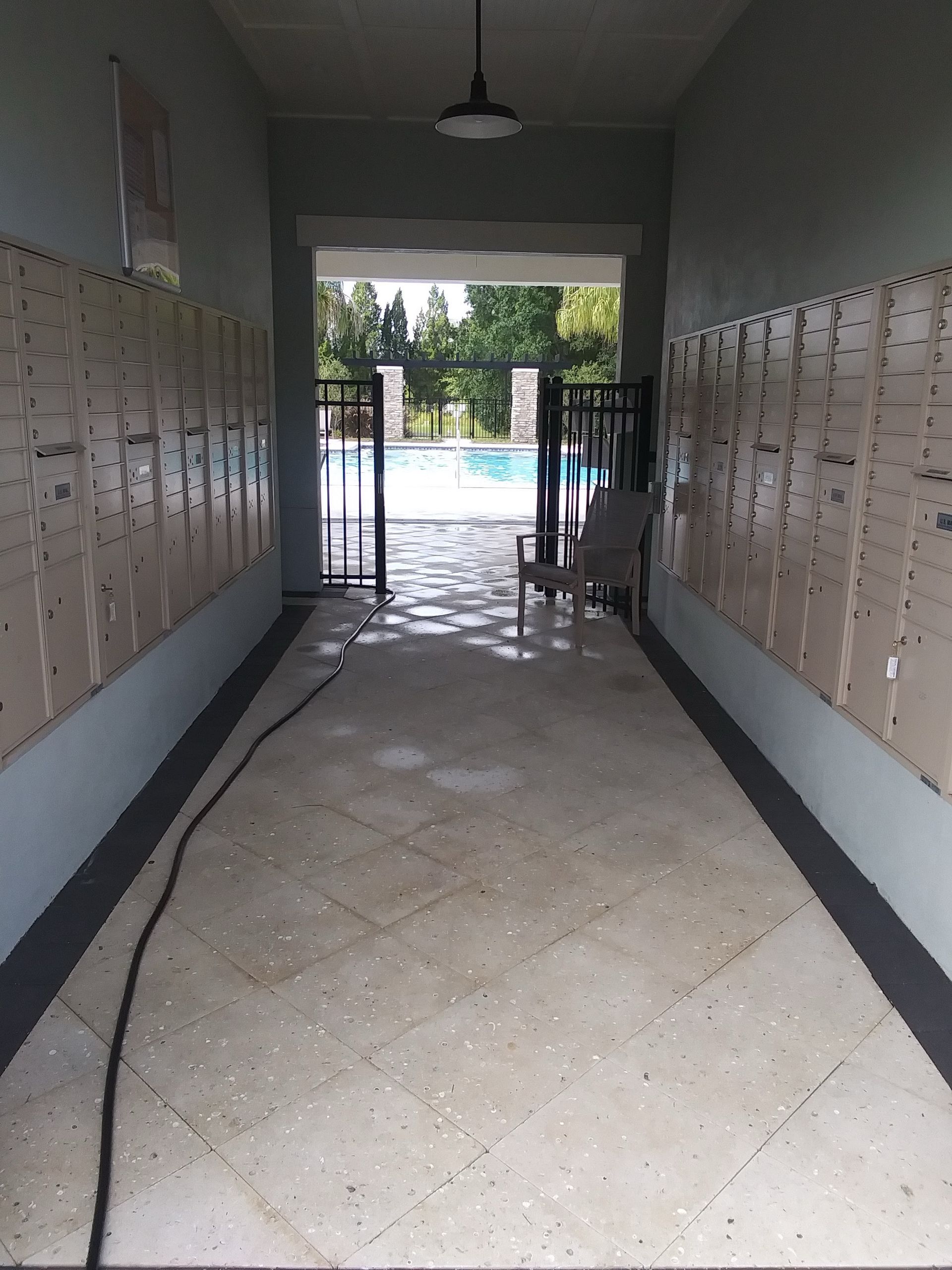 A long walkway lined with mailboxes leads to a pool area. A single chair sits by the pool.