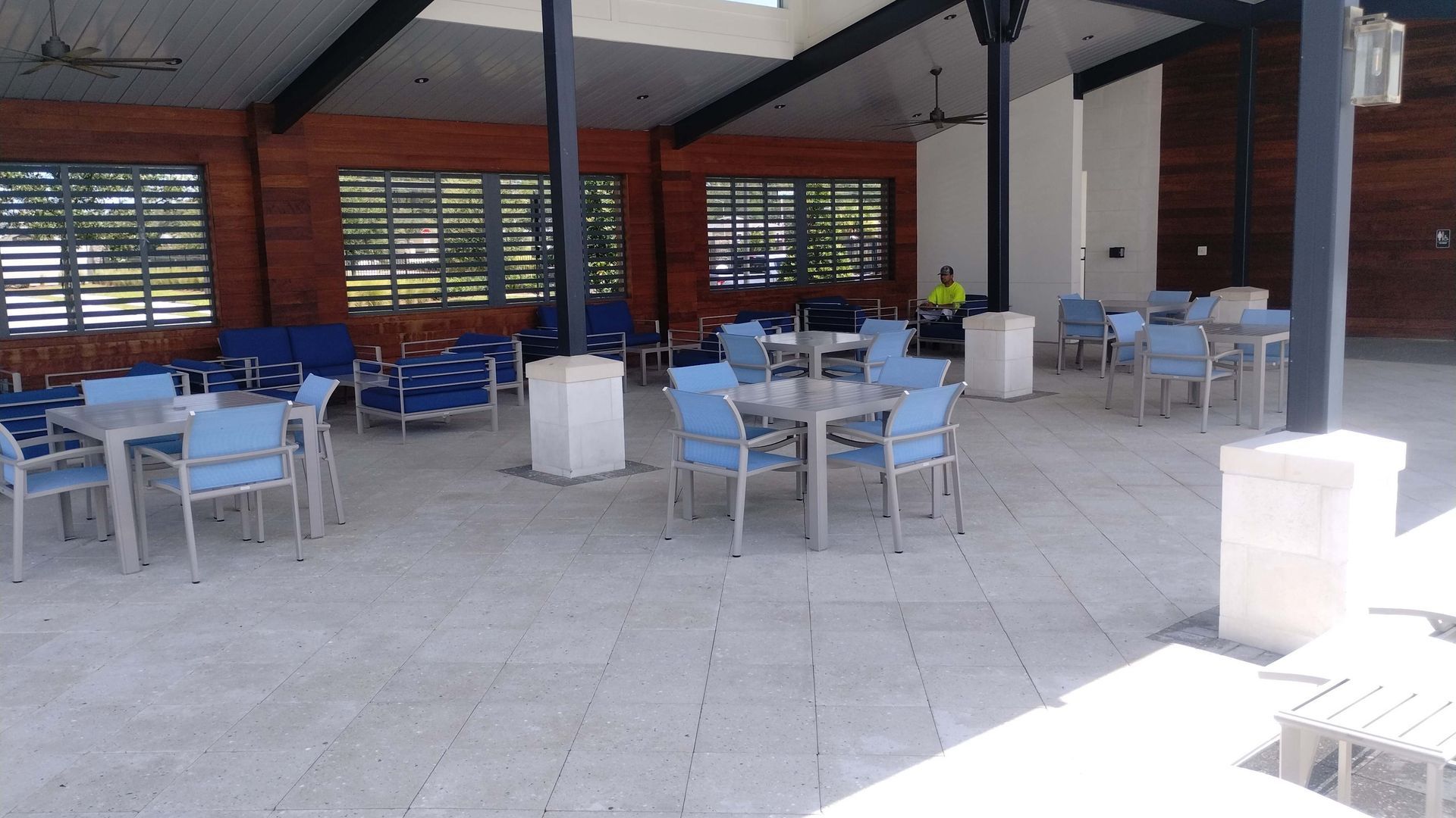 Outdoor patio with blue chairs and tables under a sloped roof.