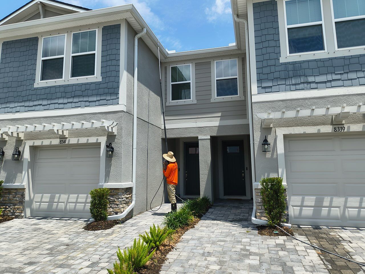 Townhomes with gray exteriors; a person in orange stands in front of the middle unit.