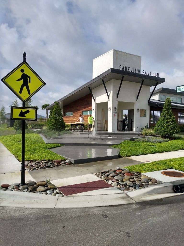 Pedestrian crossing sign in front of modern building, Preview Park. Person spraying the sidewalk.