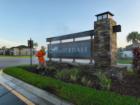 Man in orange work attire landscaping near 