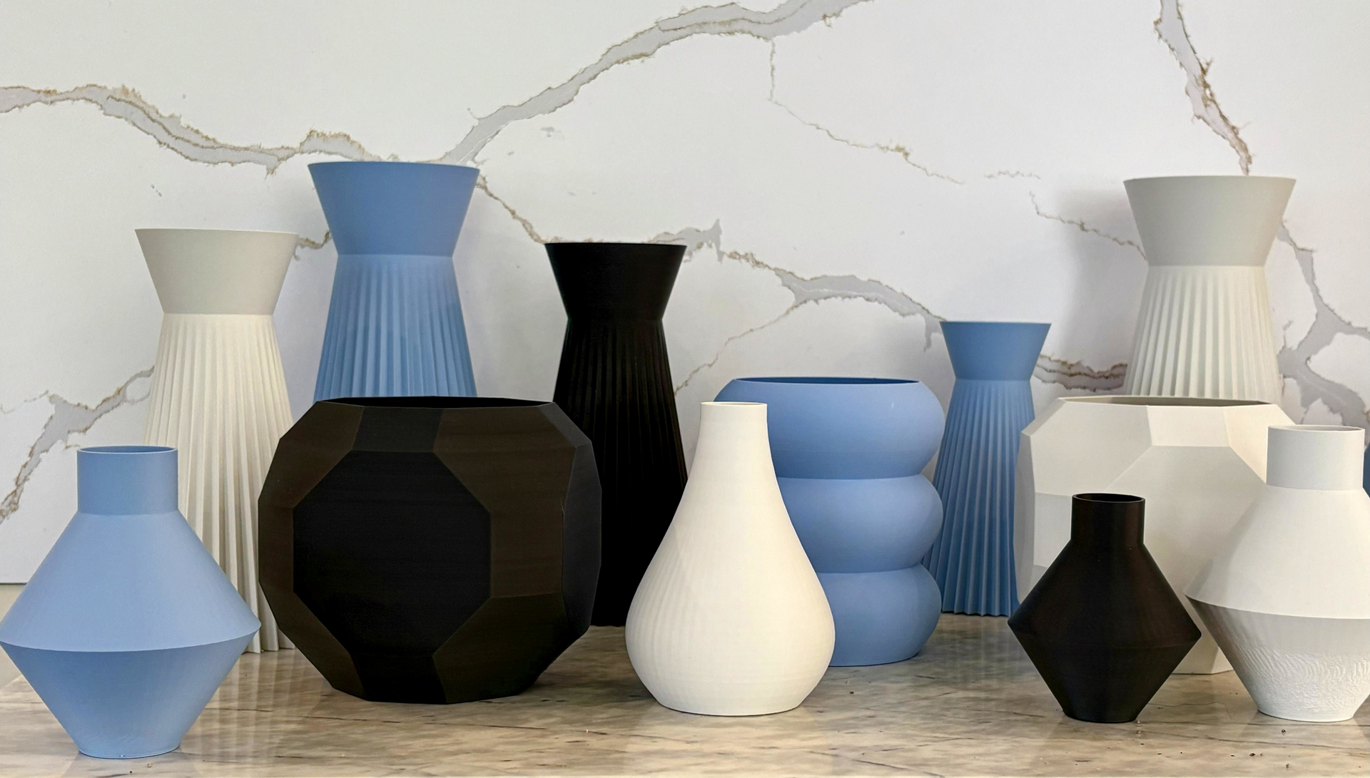 Assortment of colorful, modern vases in various shapes and sizes against a marble-patterned backdrop.