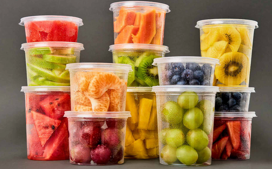 Recipientes de plástico transparente apilados sobre un fondo oscuro, cada uno lleno de diversas frutas .