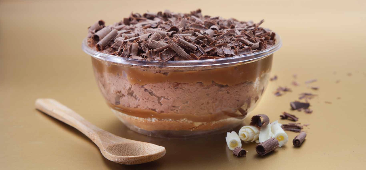 Un postre de chocolate en un cuenco transparente, cubierto con virutas de chocolate