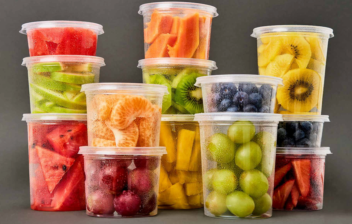 Varios recipientes de plástico transparente llenos de frutas cortadas de diversos colores, como melones, bayas y cítricos.