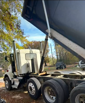 White dump truck with raised bed, outdoors.