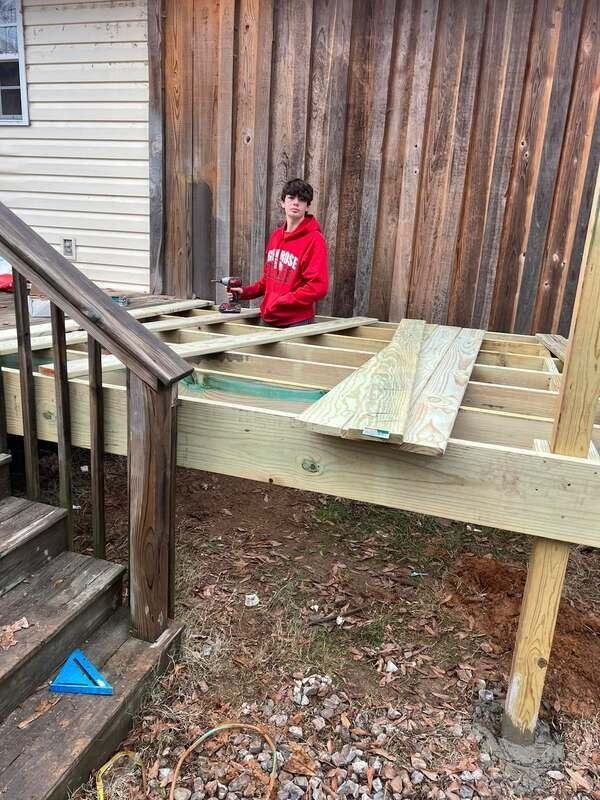 A person holding a baby up in the air indoors near a window, baby smiling.