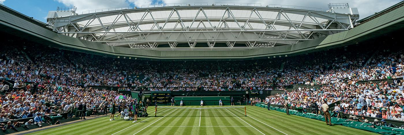 A tennis stadium filled with people watching a tennis match.