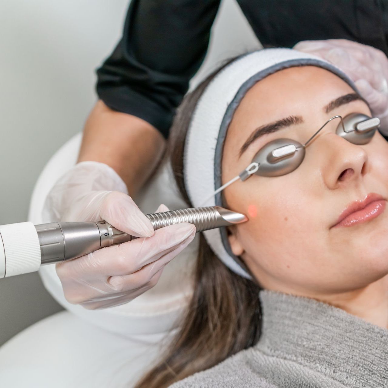 woman-with-carbon-mask-face-receiving-laser-procedures-black-glasses-by-cosmetologist-spa-salon-vertical-shot-og-woman-spa-with-facial-treatment