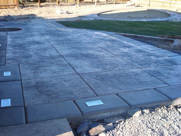 A concrete walkway is being built in a backyard.