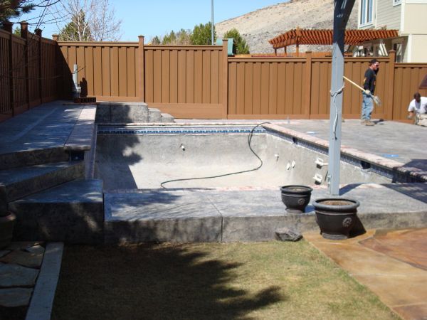 A man is working on a swimming pool in a backyard