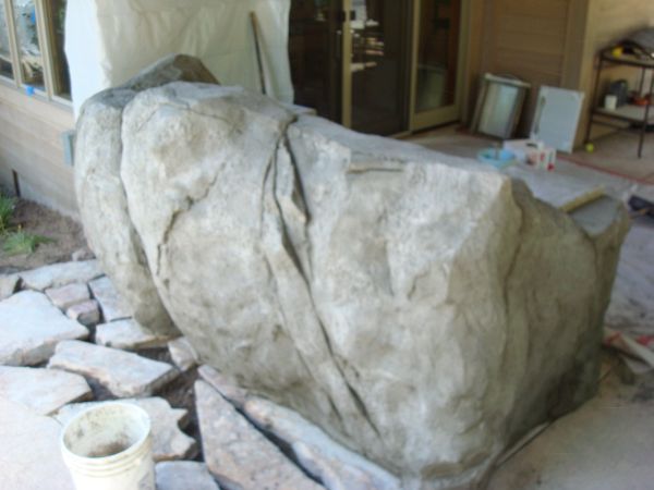 A large rock is being covered with a tarp