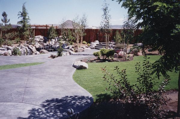 A driveway leading to a house with trees and rocks