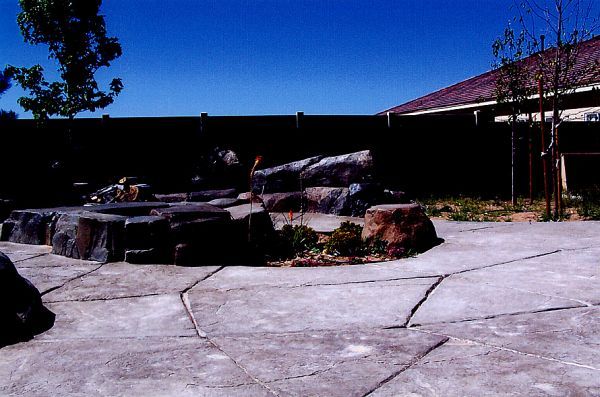 A concrete patio with rocks and a house in the background