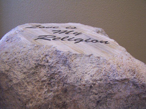 A large rock with the words love is my religion carved into it