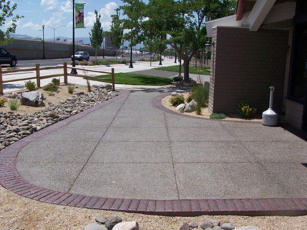 A concrete walkway with a brick border leading to a building