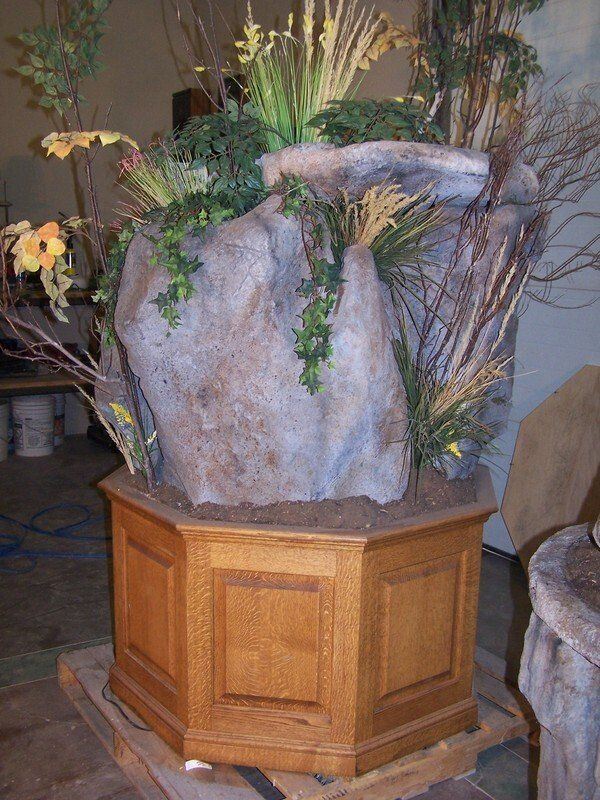A wooden planter filled with flowers and plants is sitting on a wooden pallet.