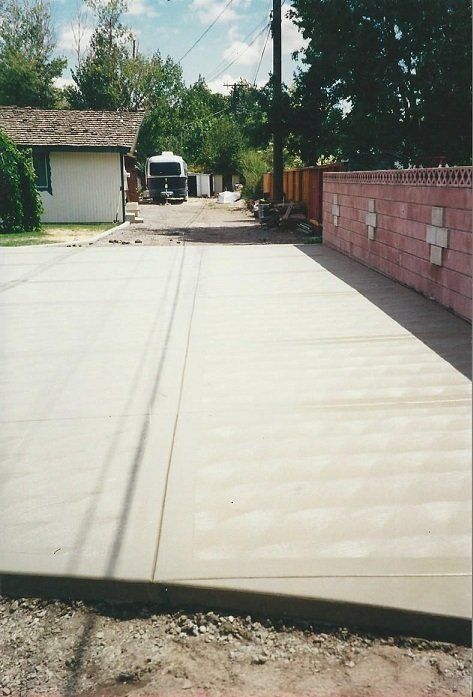A brick wall with a cross on it is next to a concrete driveway