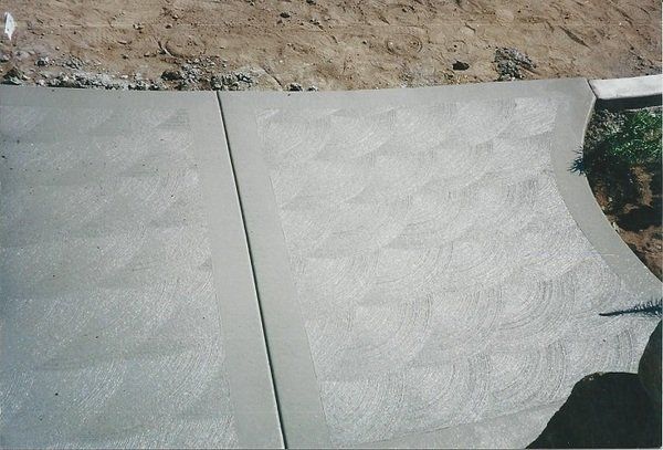 A concrete walkway is being built next to a pile of dirt.