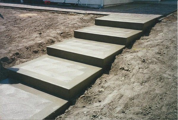 A set of concrete steps going up a dirt hill