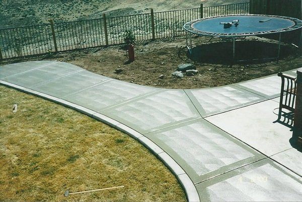 A trampoline sits in the middle of a concrete driveway