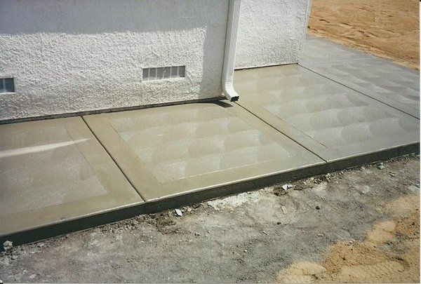 A concrete walkway is being built in front of a house