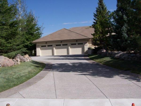 A driveway leading to a house with three garage doors