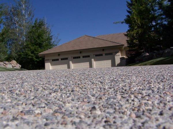 A house with three garage doors is behind a gravel driveway