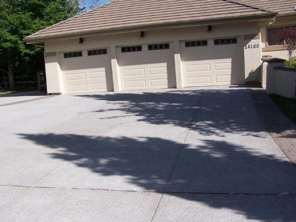 A driveway leading to a house with three garage doors