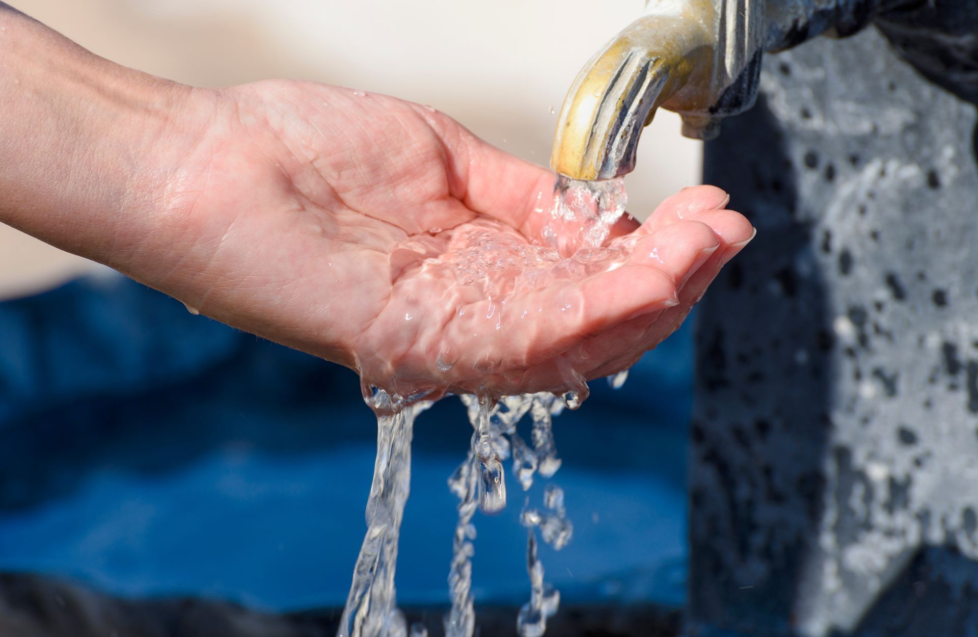 Water pours into the hand from a drinking fountain. Selective focus.