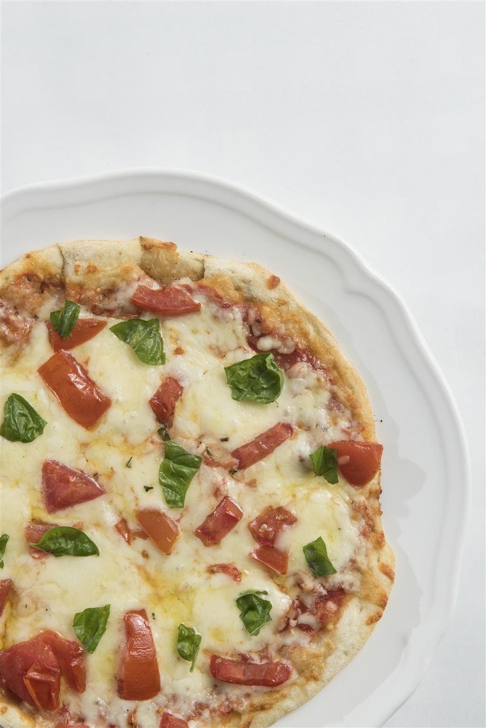 Cheese pizza topped with tomtoes and fresh basil