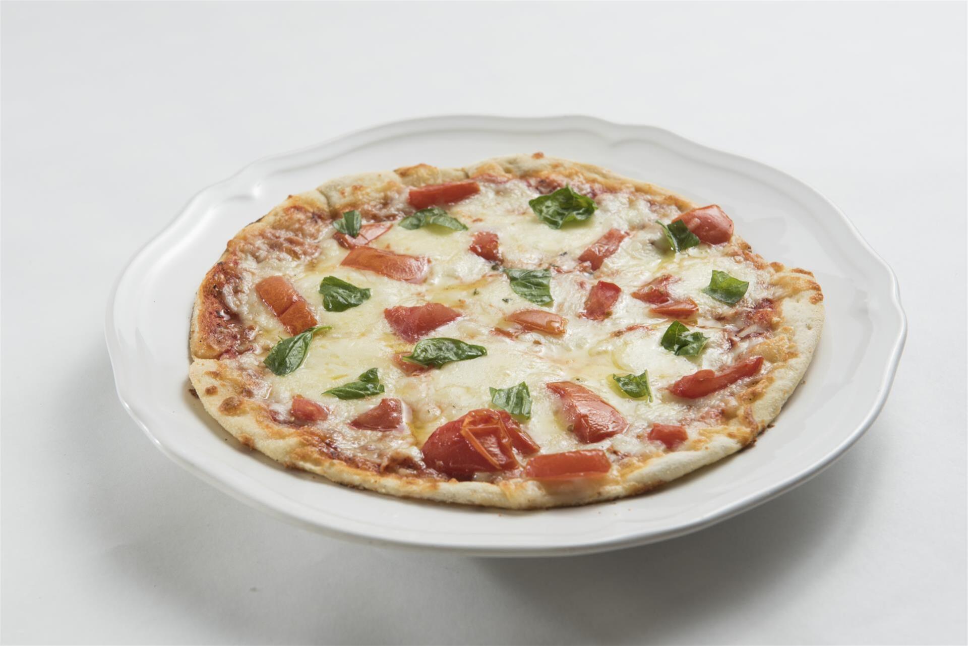 Cheese pizza topped with tomatoes and fresh basil