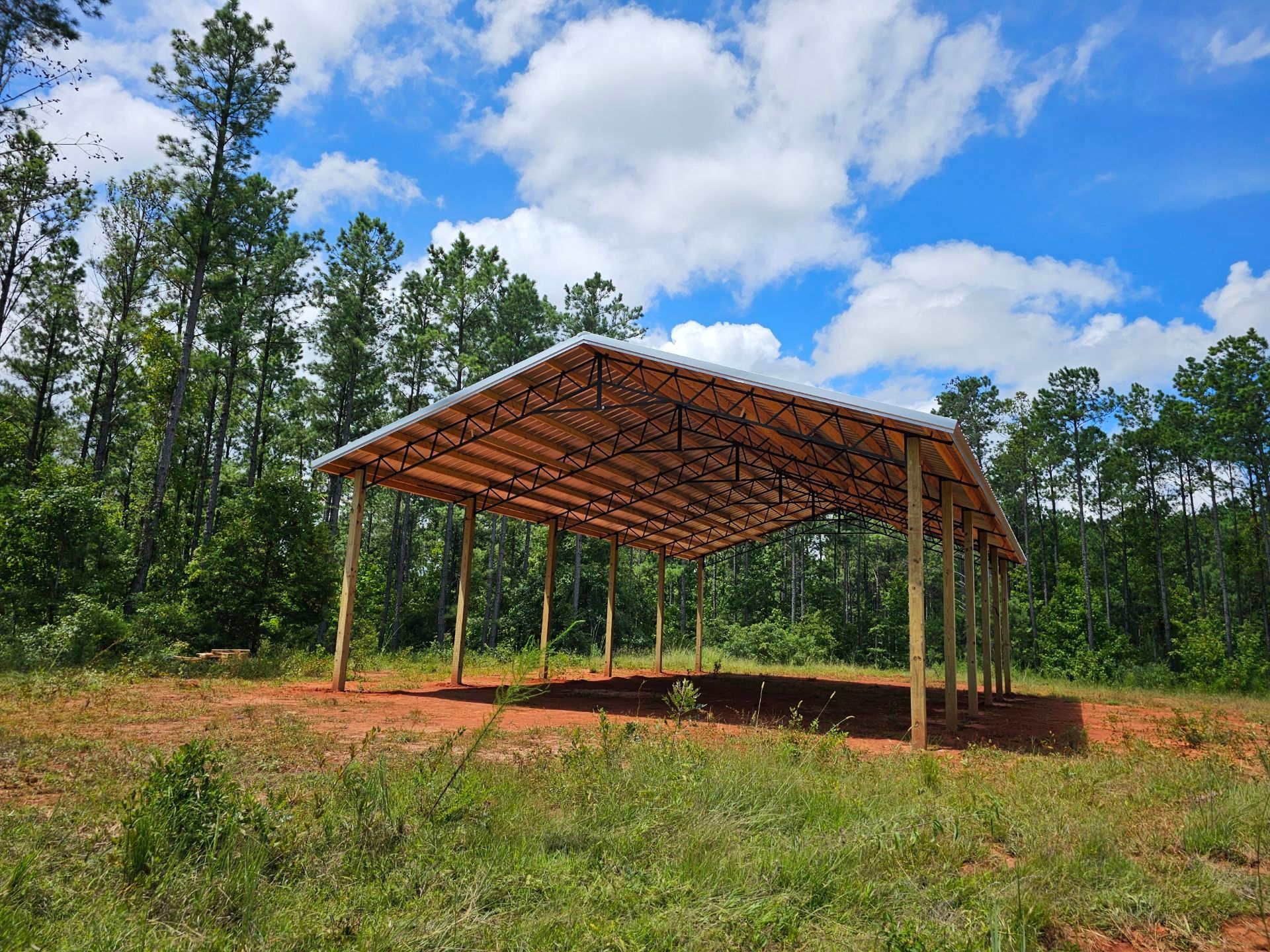 A wooden structure in the middle of a field with trees in the background.