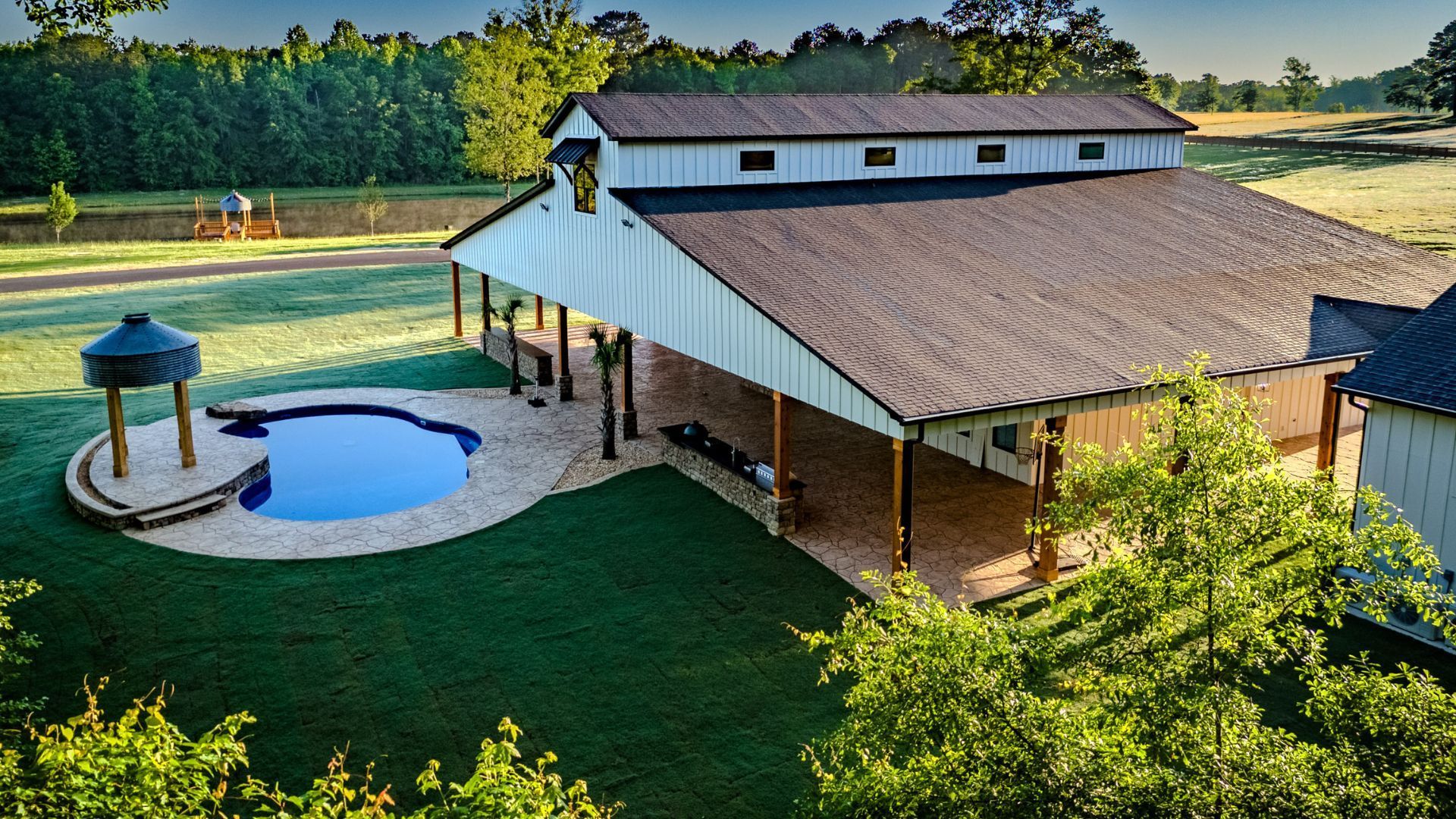 An aerial view of a barn with a pool in the backyard