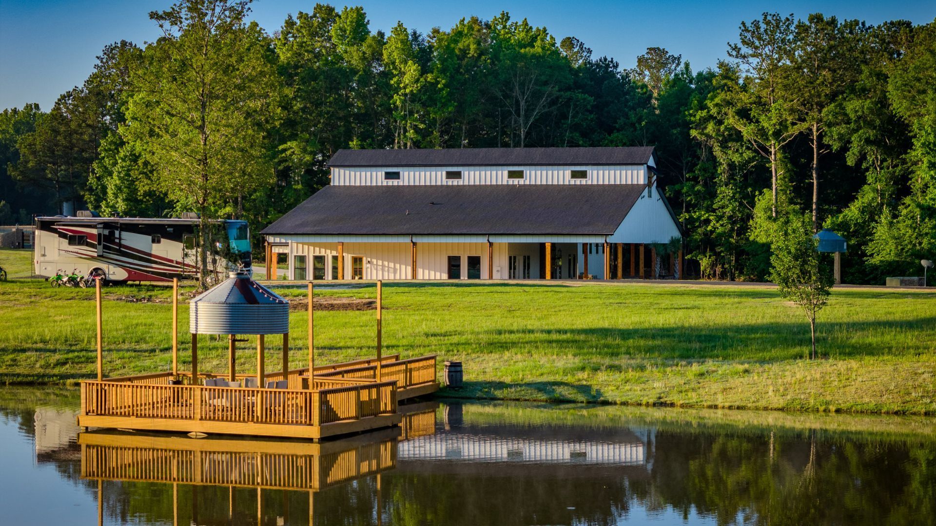 A house is sitting on top of a lush green field next to a body of water.