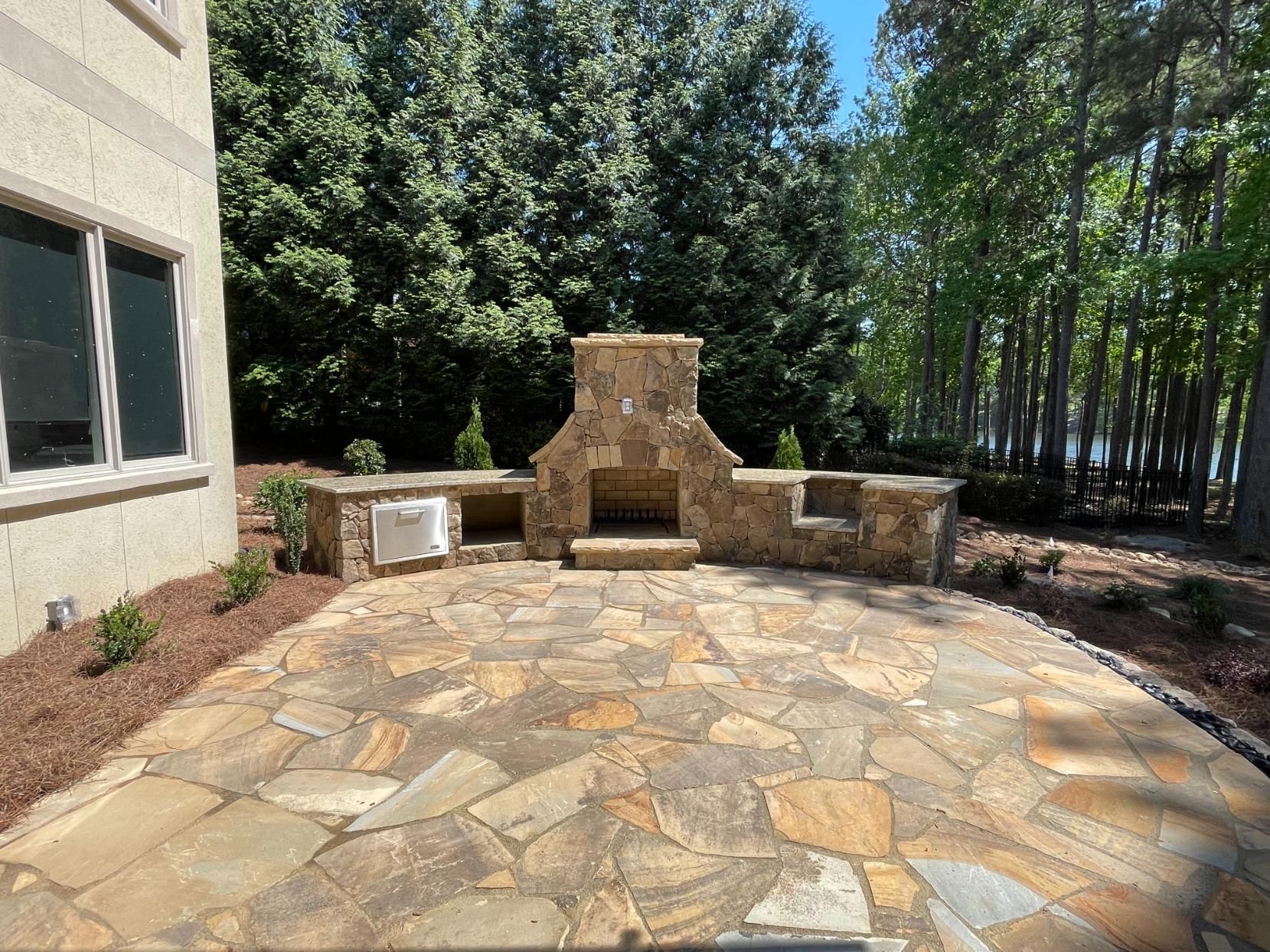 A stone patio with a fireplace in the middle of it.