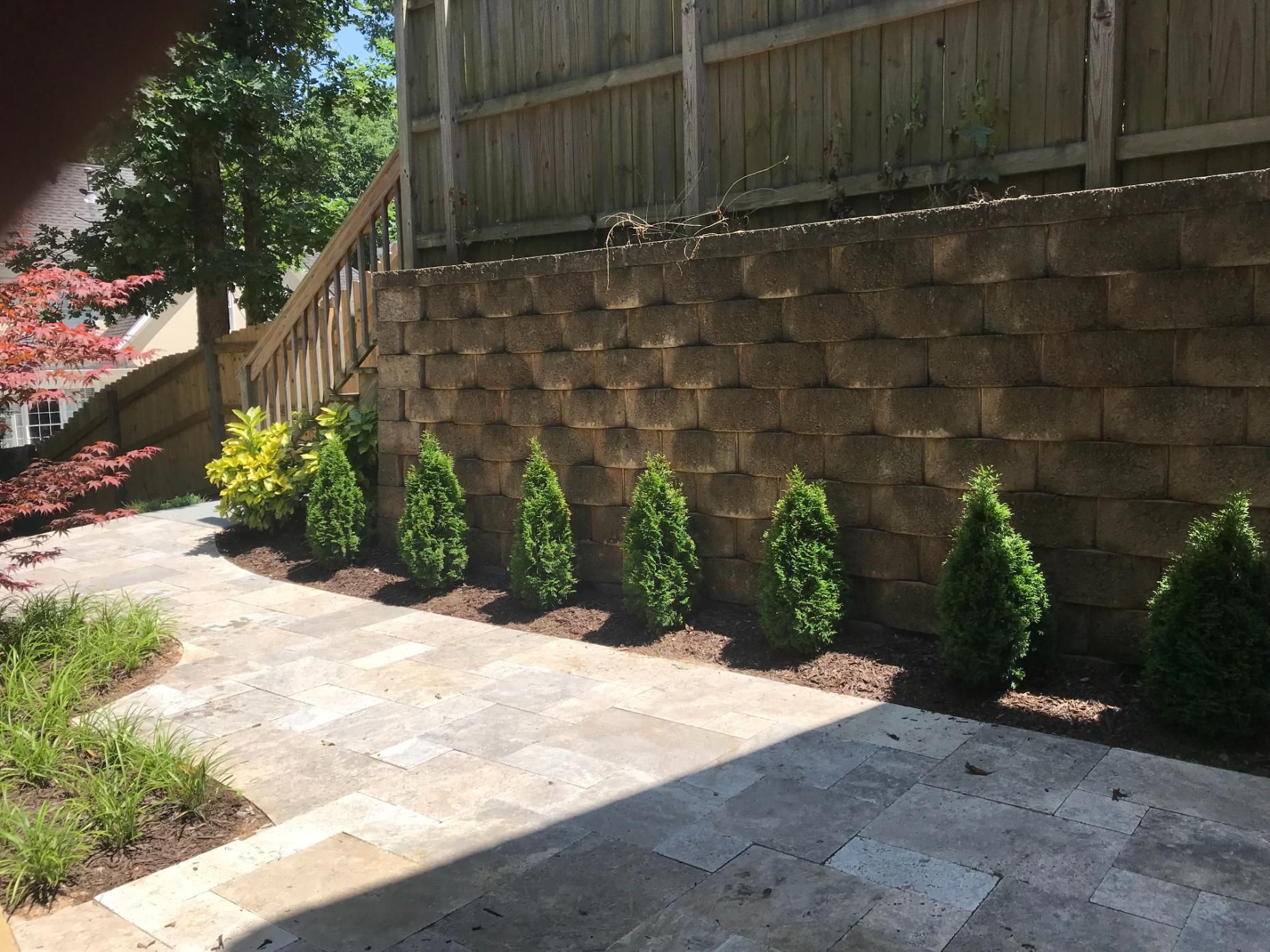 A stone wall with a wooden fence behind it.