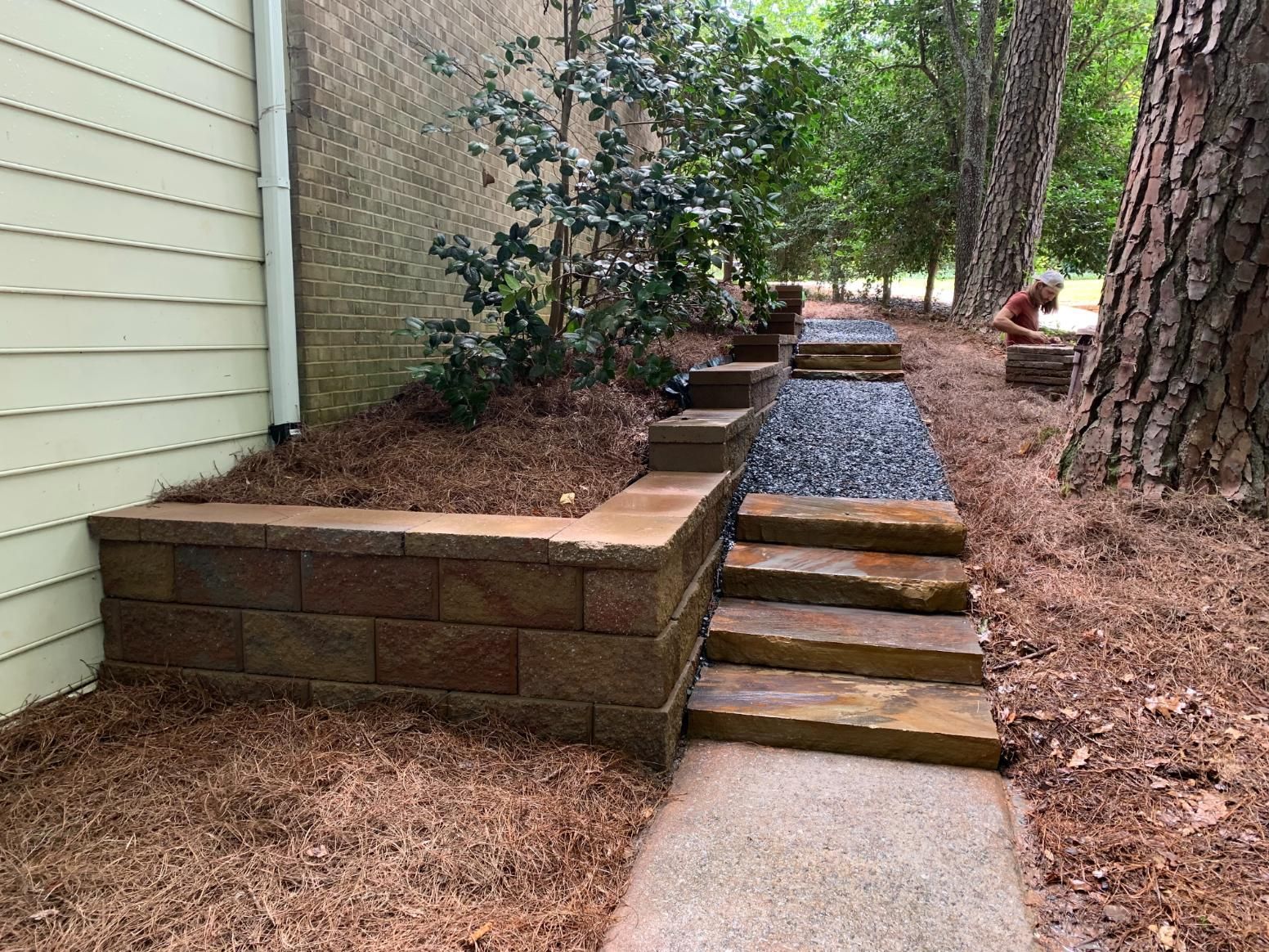A brick wall with stairs leading up to it next to a house.
