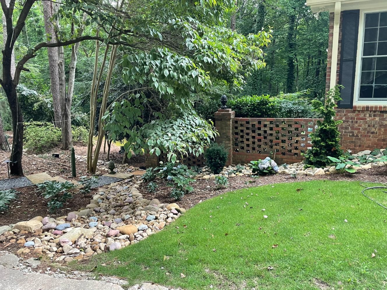 A house with a lush green lawn and trees in front of it.