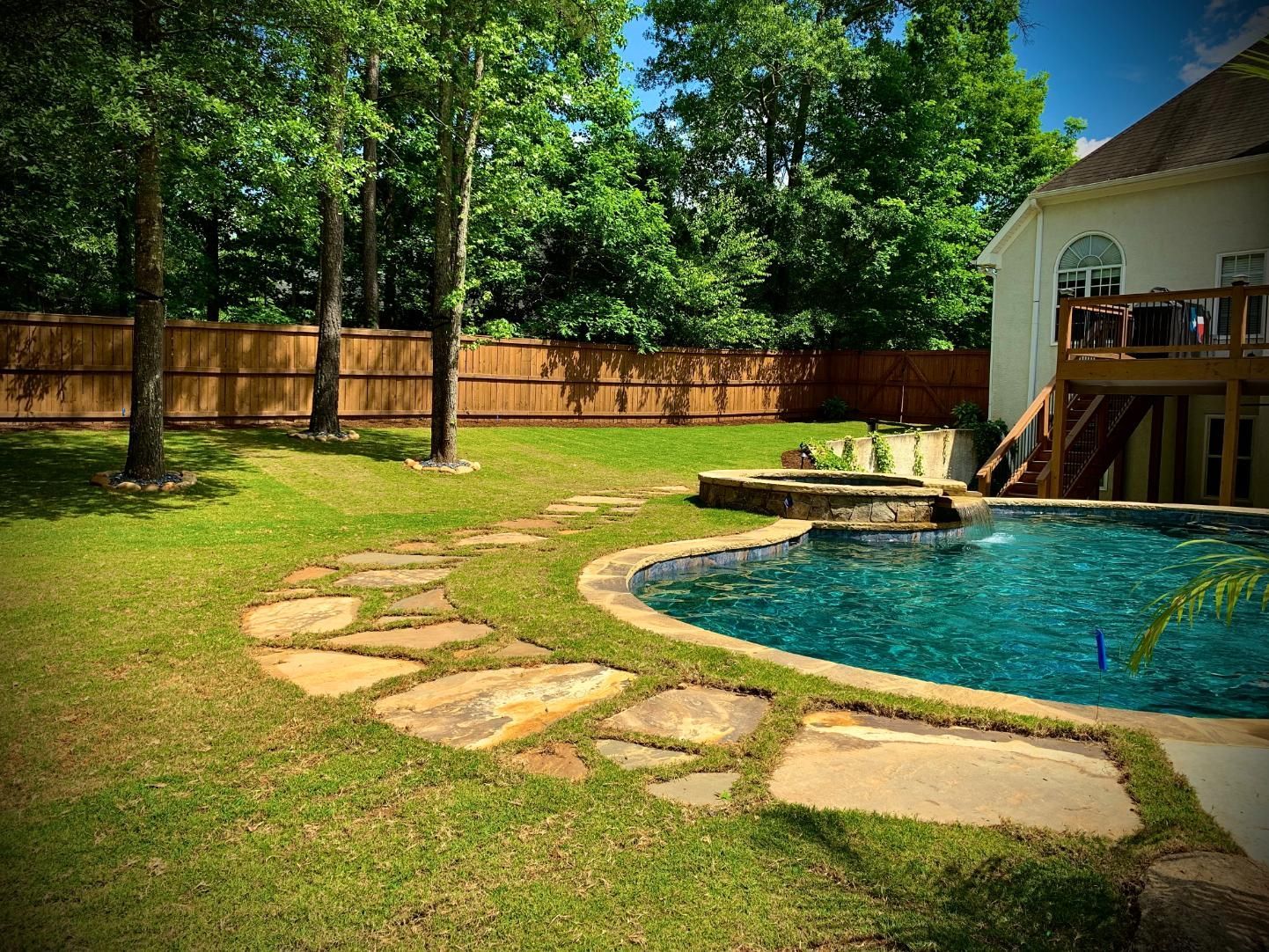 There is a large swimming pool in the backyard of a house.