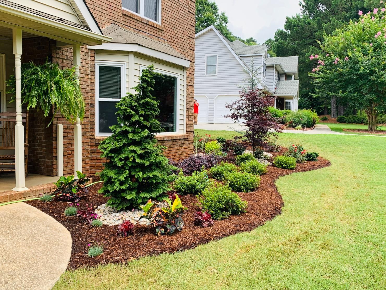 A brick house with a lush green lawn in front of it.