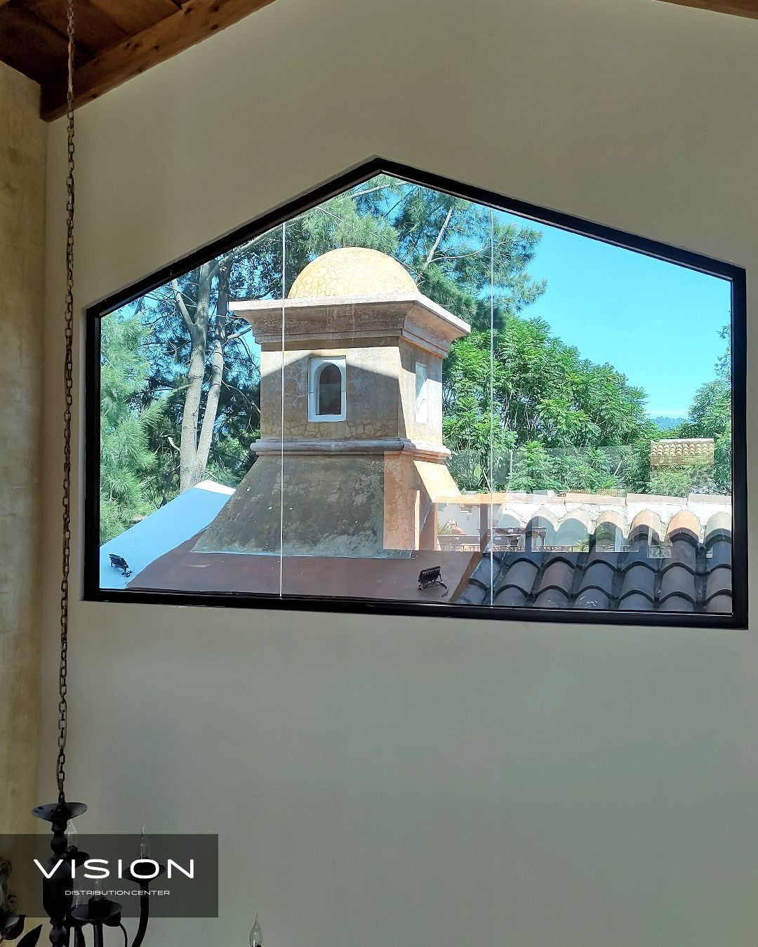 A large window with a view of a chimney and trees.