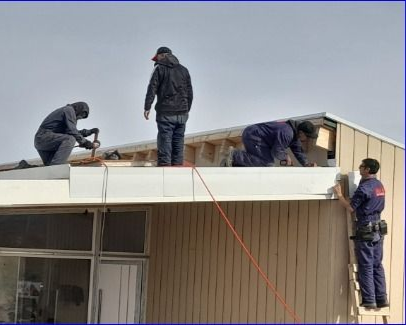 Dos trabajadores de la construcción construyen un marco de techo de madera al aire libre en un día soleado.