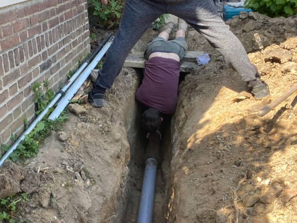 A Man and a Woman are Working in a Trench next to a Brick Wall. — Peoria, IL — Rooter-Matic Sewer Drain and Septic