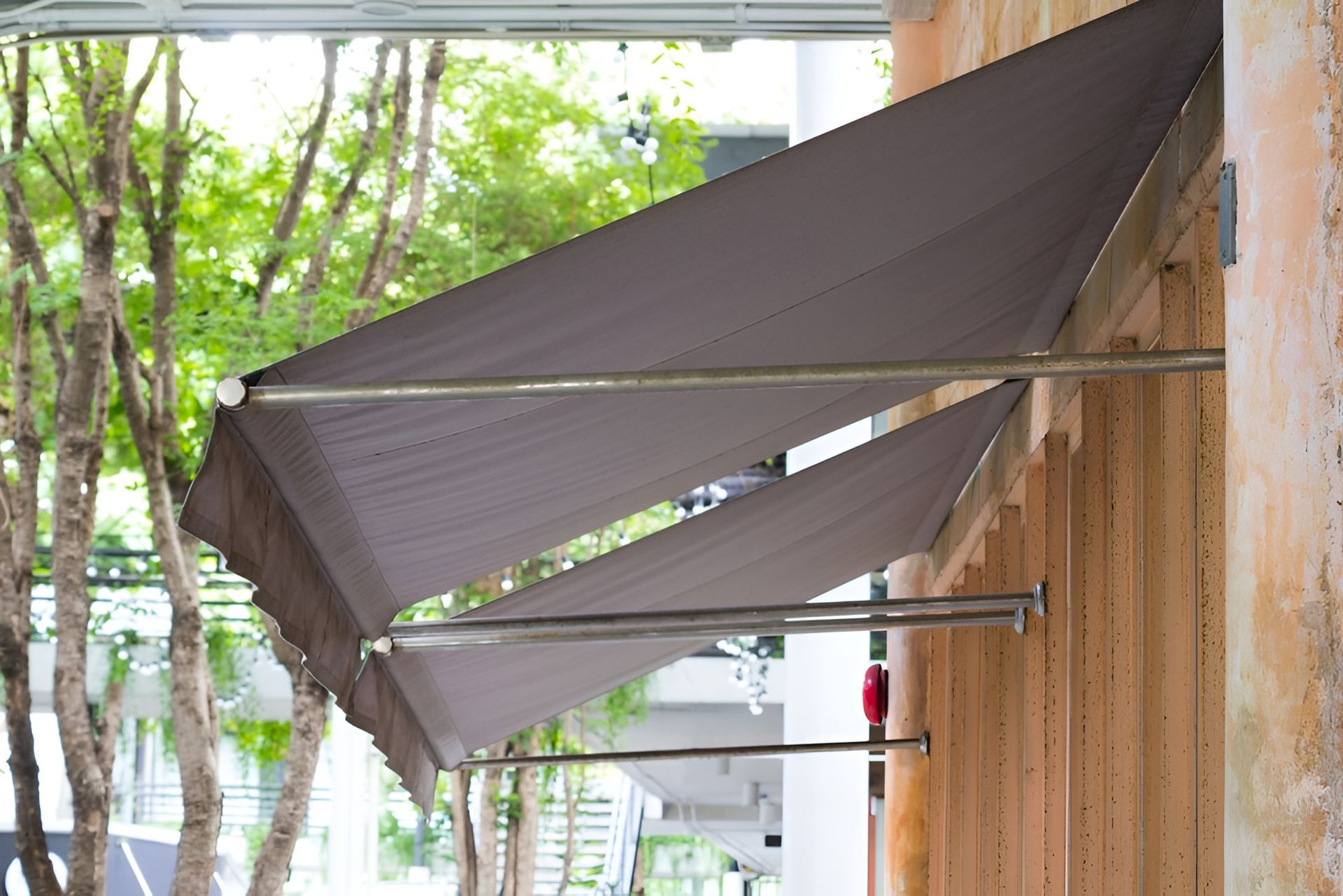 Three Retractable Gray Awnings Attached to A Tan and Brown Building — BlindDESIGN in Byron Bay, NSW