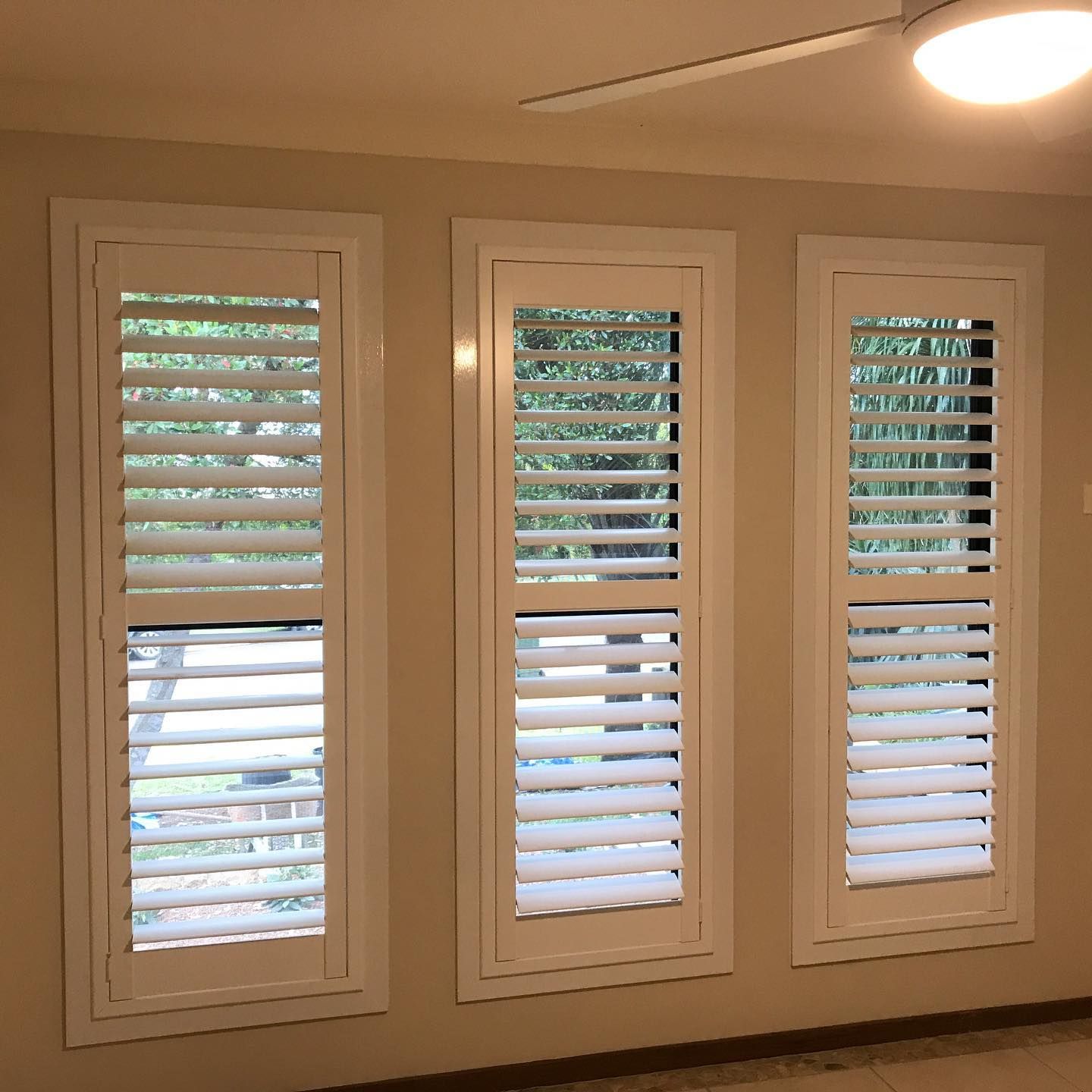 Three White Framed Windows With Closed White Shutters on a Beige Wall — BlindDESIGN in Lismore, NSW